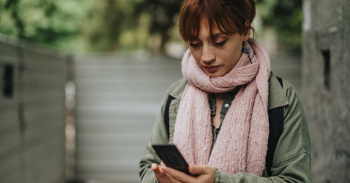 Woman wearing scarf looking at her phone, searching for anxiety therapy in Fresno.